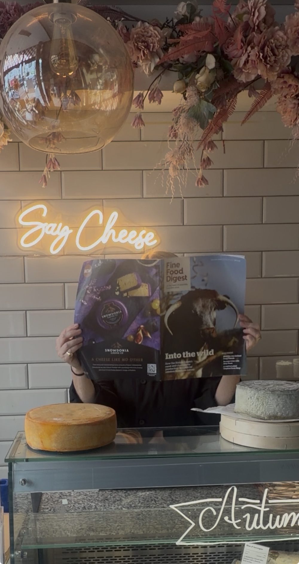 Morgan McGlynn Carr reading Fine Food Digest behind the counter at Cheeses of Muswell Hill