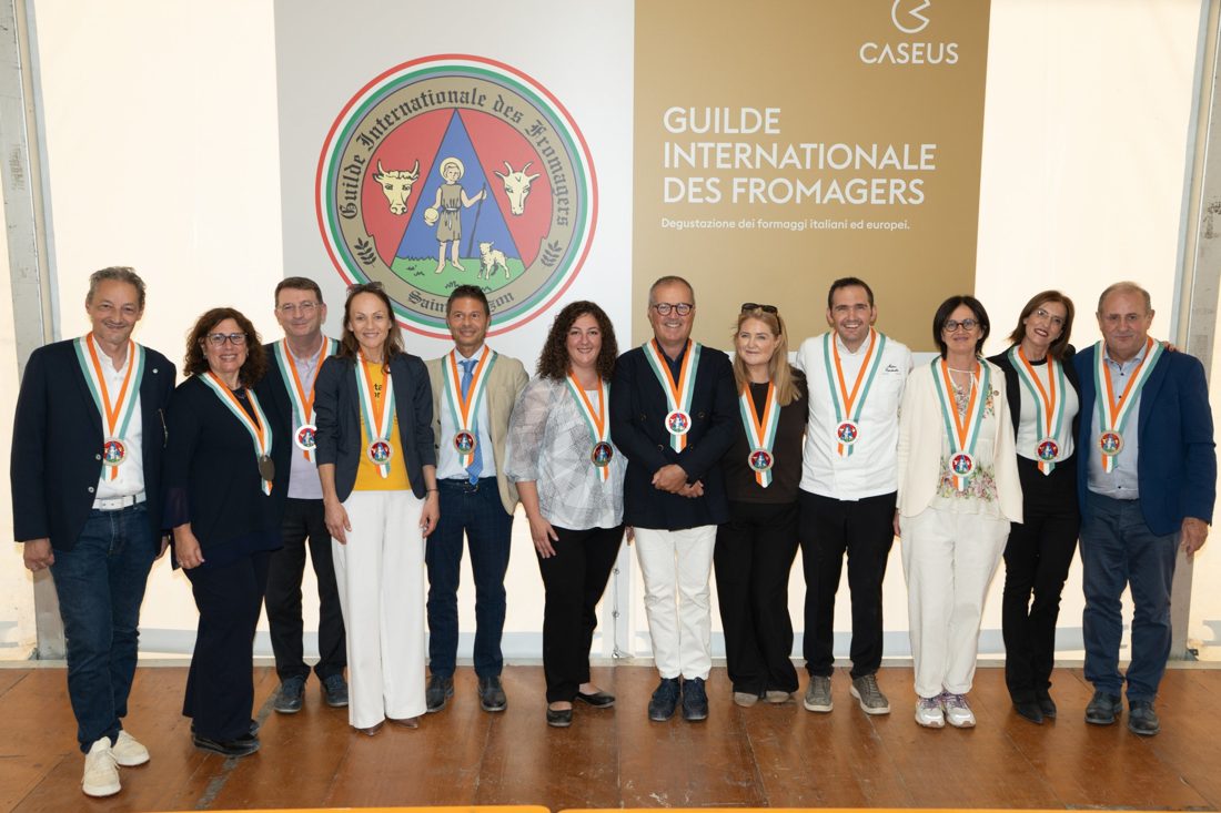 Morgan McGlynn Carr with fellow Guilde Internationale des Fromagers inductees beneath the Guilde crest